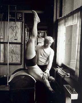 Joseph Pilates assisting a student with a leg stretch