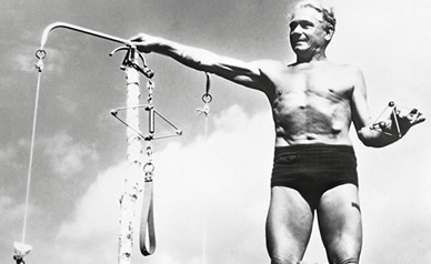 Joseph Pilates demonstrating a spring-based exercise apparatus